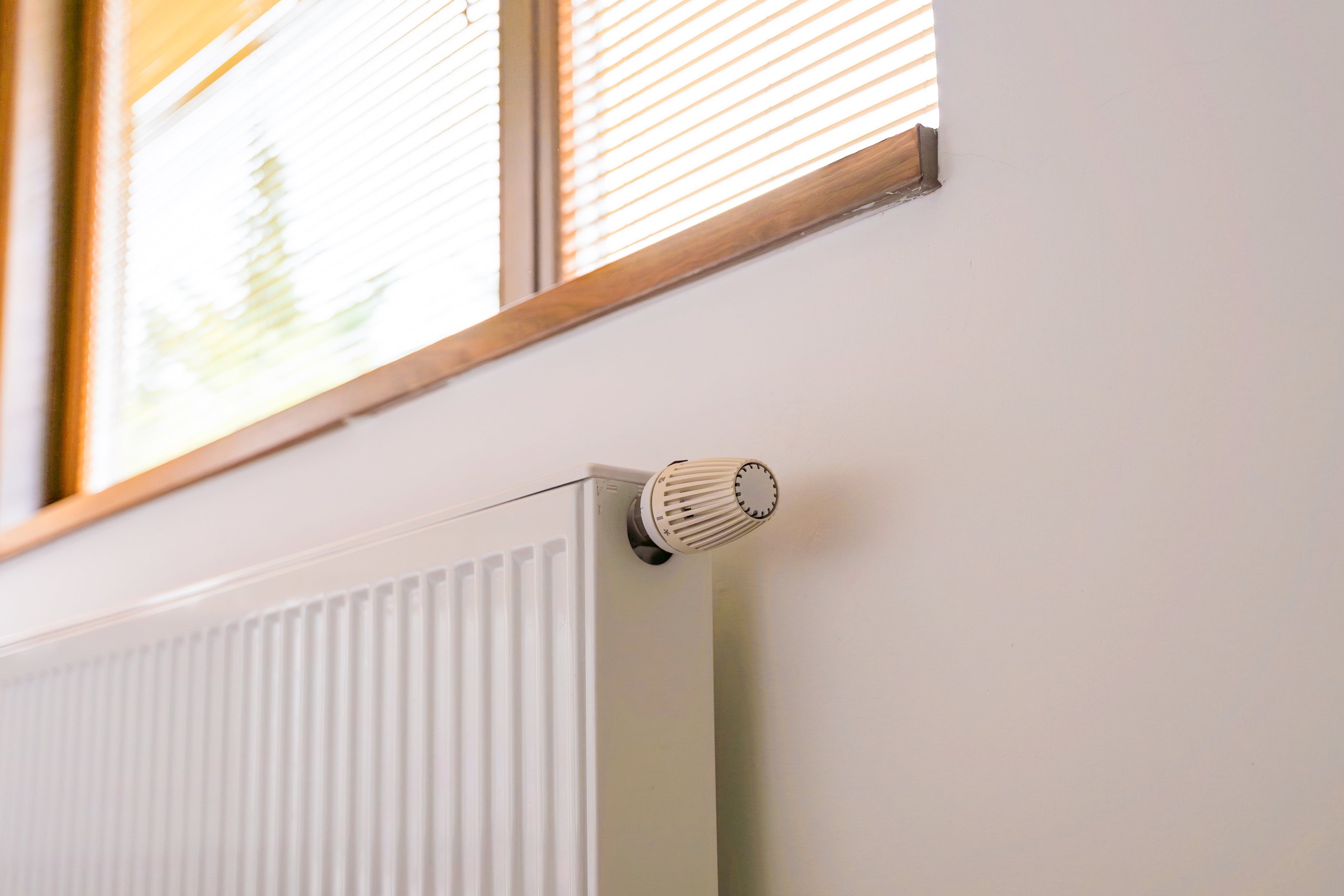 Heizkörper unter einem Fenster, durch das die Sonne scheint.
